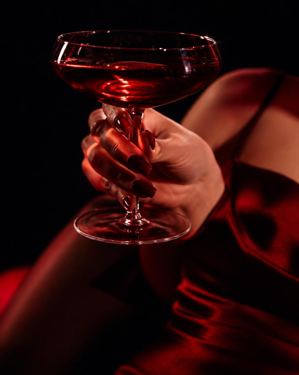 Mano che tiene una coppa con cocktail rosso